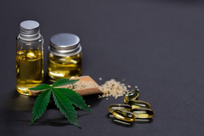 cannabis oil and capsules beside a cannabis leaf